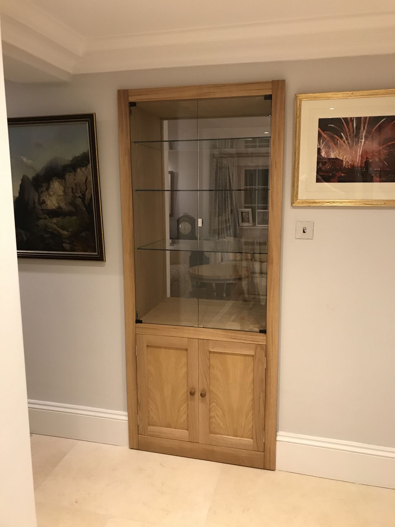 Oak display cabinet with glass doors, built into a hallway wall