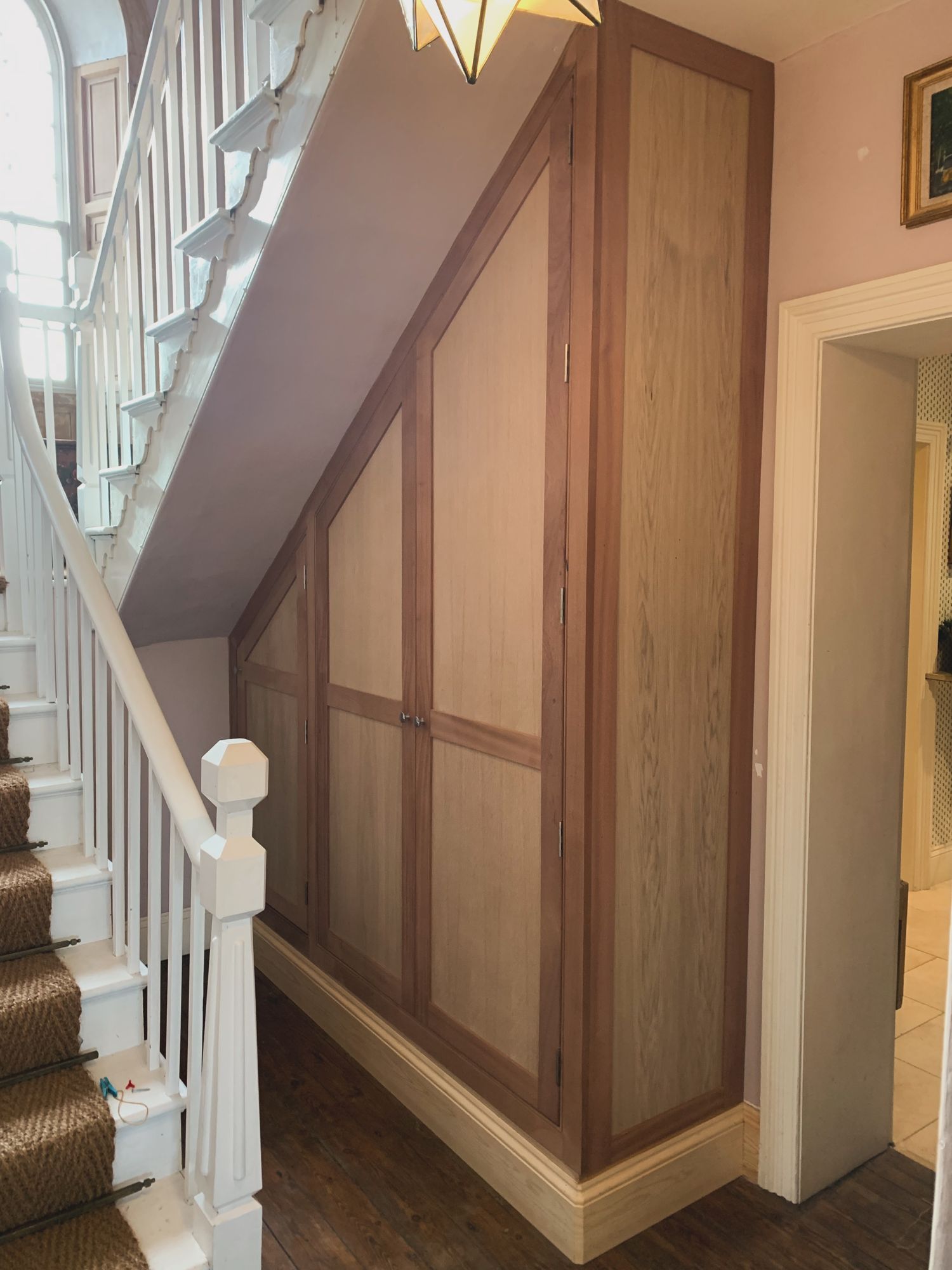 Under-stairs cupboards in oak veneer with a sapele frame in a period hallway